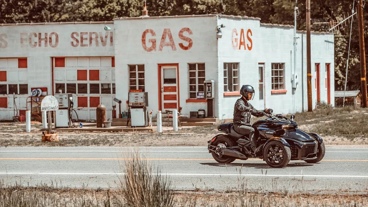 Can-Am Spyder на дороге рядом с бензоколонками.