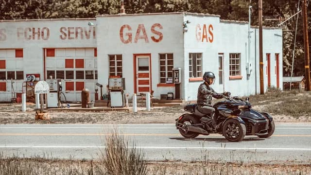 Can-Am Spyder на дороге рядом с бензоколонками.