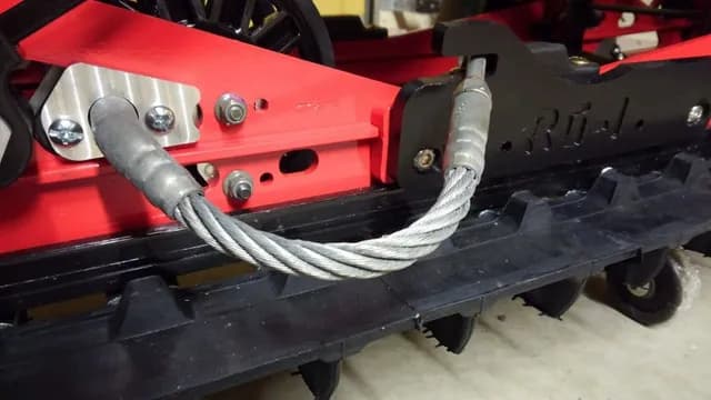 Тросовый скребок на красной направляющей подвески снегохода Polaris