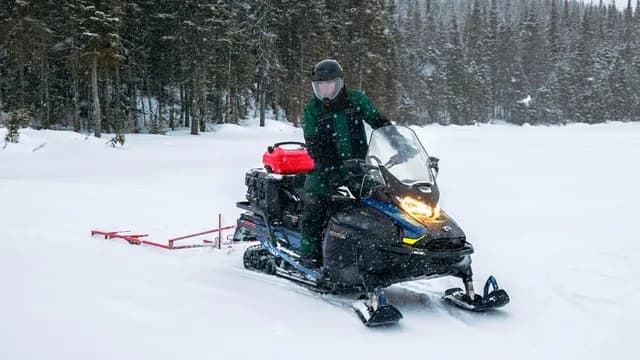 Водитель Ski-Doo Skandic SE буксирует прицепное оборудование по снегу