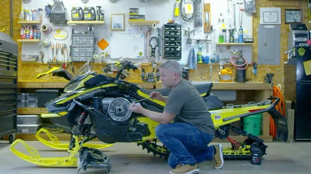 Механик обслуживает Ski-Doo со снятой боковой панелью в мастерской