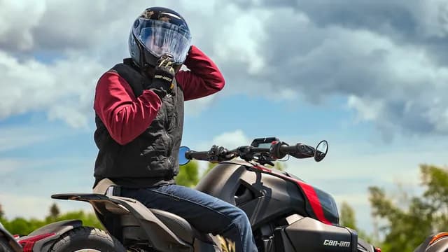 Водитель Can-Am Ryker застёгивает шлем перед поездкой.