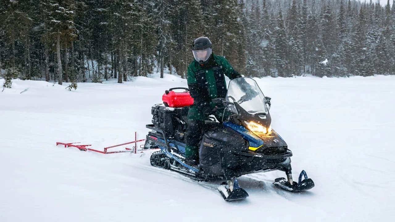 Водитель Ski-Doo Skandic SE буксирует прицепное оборудование по снегу