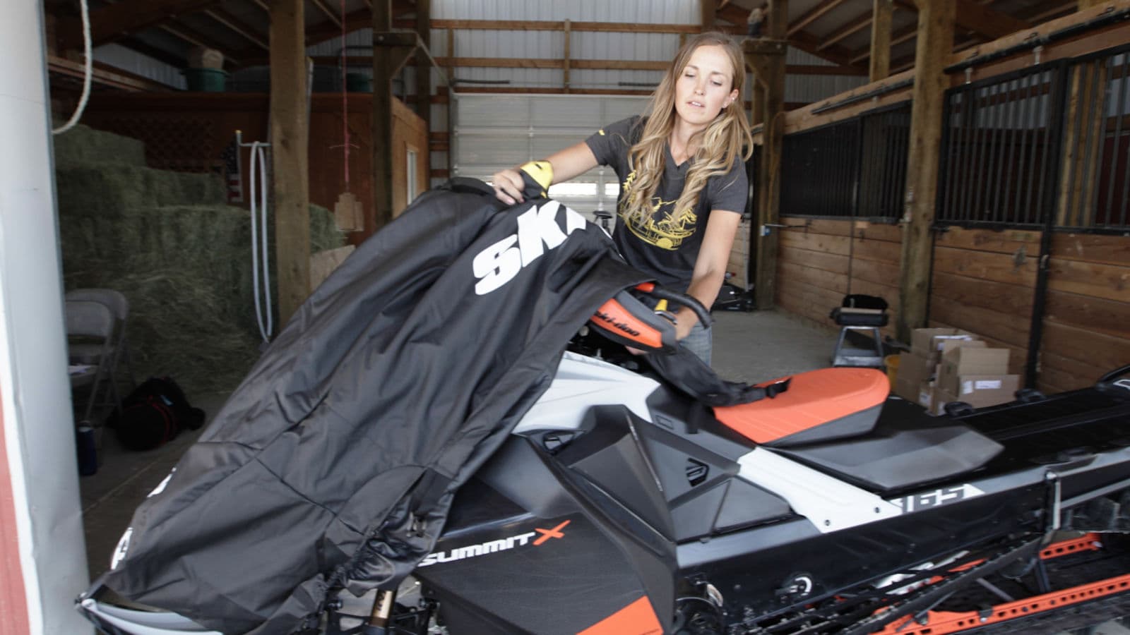 Женщина надевает чехол на Ski-Doo Summit в помещении