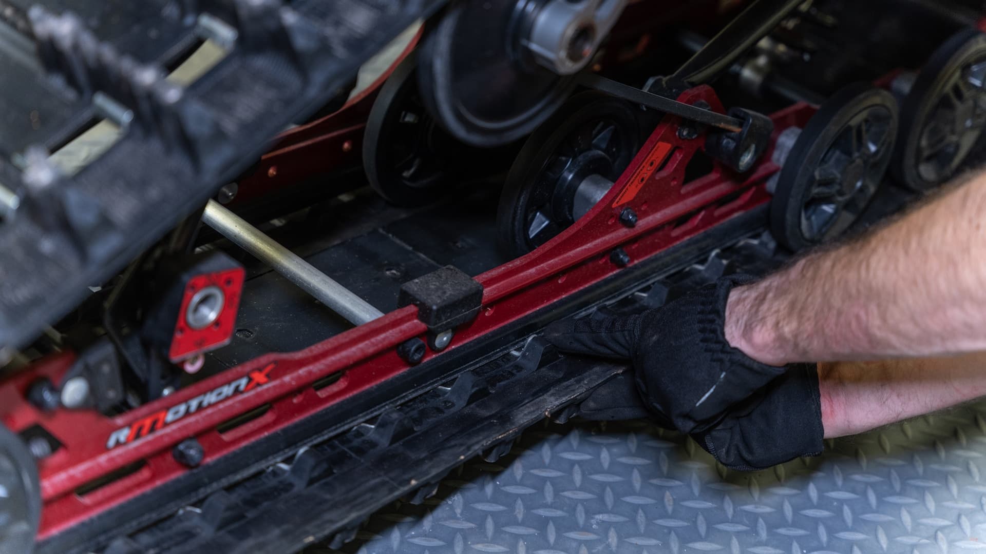 Рука механика у направляющей и окон гусеницы Ski-Doo