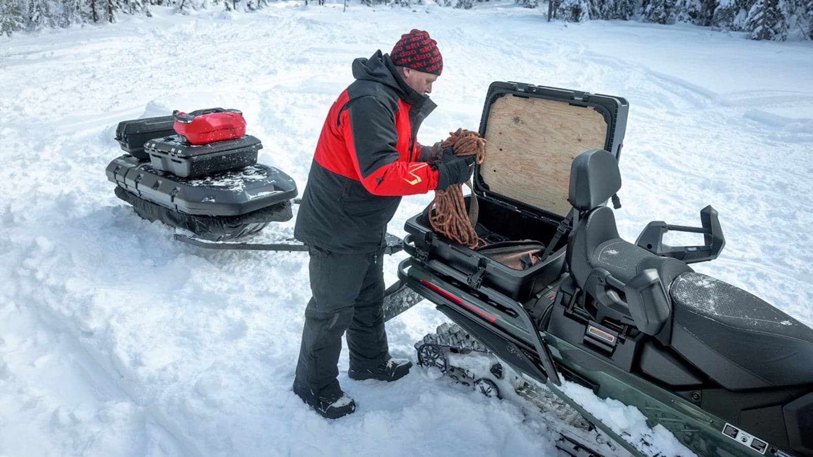 Райдер укладывает снаряжение в багажный отсек Ski-Doo Expedition в снегу
