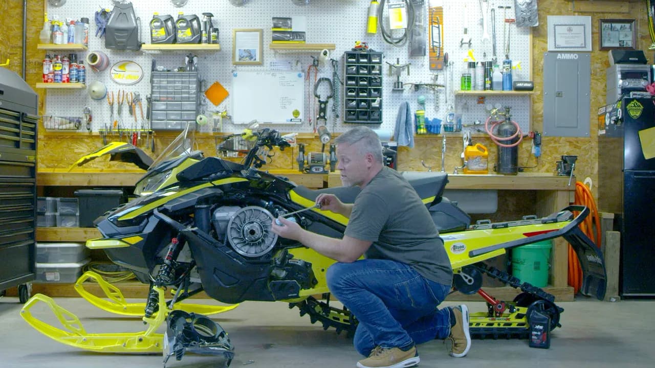 Механик обслуживает Ski-Doo со снятой боковой панелью в мастерской