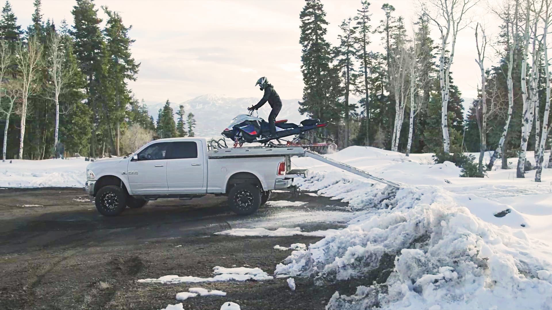 Водитель завершает погрузку Ski-Doo по рампе на платформу пикапа