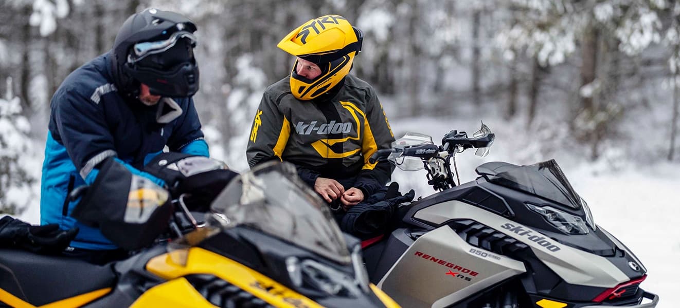 Два водителя рядом со снегоходами Ski-Doo на зимнем маршруте