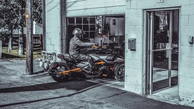 Дорожный трицикл Can-Am у гаража.